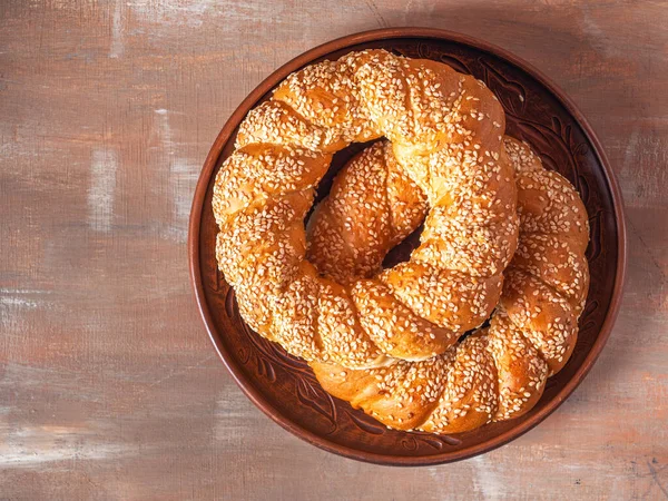 Fresh baked goods, twisted sweet rolls with sesame seeds on a brown ceramic plate