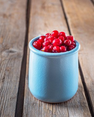 Kil mavisi bir kavanozdaki taze kızılcıklar ahşap bir masa üzerinde yakın plan