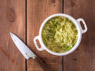 Salata hazırlama, ince doğranmış taze lahana ve beyaz plastik tencere.