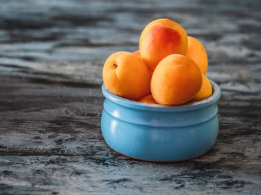 Gri arka planda seramik mavi bir kavanozda kayısıların yakın plan görüntüsü.