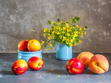 Taze meyveler ve sarı tecavüz yaz çiçekleri masada.