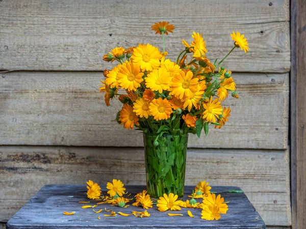 Bouquet orangefarbener Ringelblume im Glas auf einem Hocker — Stockfoto