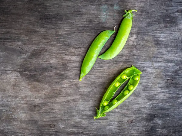 Vainas jóvenes de guisantes verdes en una mesa de madera — Foto de Stock