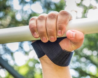Spor aletleri ve spor aletleri için sabit bir pozisyon için sabit bir kayış ile kol, ve bir yaz günü yatay bar yakın esneme.