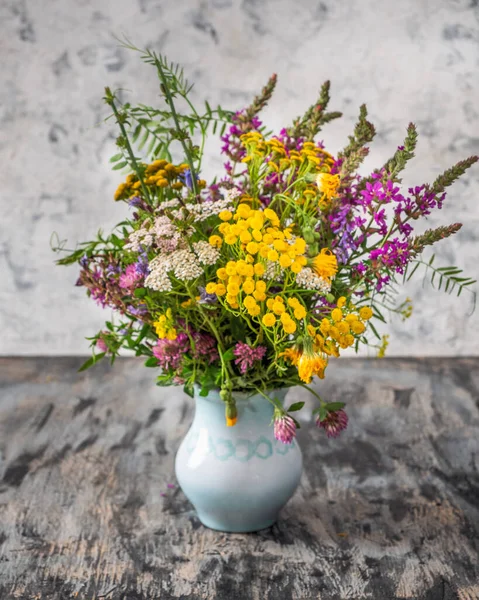 Lush bouquet of field flowers in a blue vase close-up