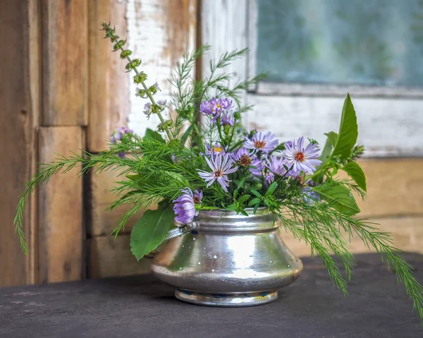 A small bouquet of wildflowers and blue New Belgian asters in a metal sugar bowl — Stock Photo, Image