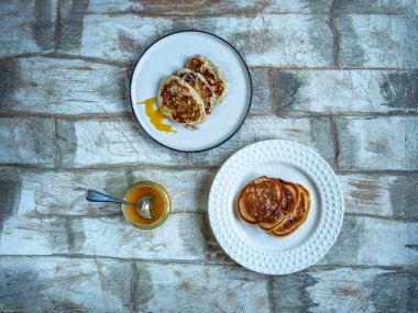 İki hafif tabakta elmalı gözleme ve lezzetli bir kahvaltı için cam kavanozda meyve balı.
