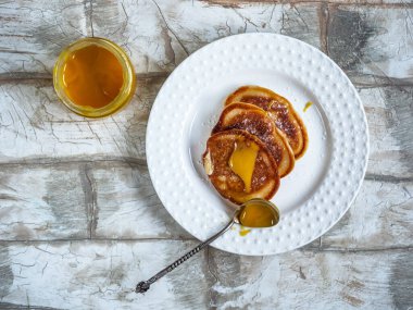 Hafif bir tabakta elmalı gözleme ve hafif bir arka planda kahvaltıda taze bal ile bir kaşık.