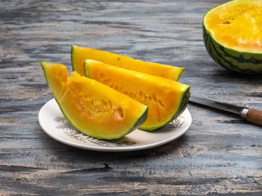 Dekoratif seramik tabakta yakın plan sarı karpuz dilimleri.