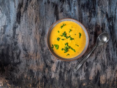 Gri ve siyah arka plan manzaralı koyu gri tabakta fesleğen çorbası.