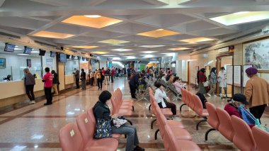 Taipei, Tayvan, 18 Aralık 2025. Hastalar servis sayaçları ve dijital kuyruk göstergeleriyle hastane resepsiyonunda bekliyorlar