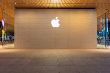 Taipei, Tayvan - 20 Aralık 2025: Aydınlatılmış logo ve eğimli cam cepheli Apple Store 'un dışı, içerideki müşteriler görülebilir