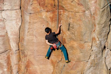 Keelung, Tayvan - Ocak 06 2026: Kaya tırmanışçısı kask ve ip takarak dikey kumtaşı uçurumuna çıkıyor