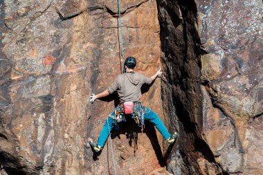 Keelung, Tayvan - Ocak 06 2026: Tırmanma teknikleri ve tırmanma teçhizatlarının altını çizen sivri kaya formasyonlarına karşı halatla bağlanmış koşumlu dağcı ile spor tırmanışı sahnesi
