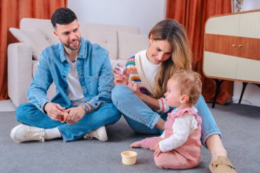 Mutlu genç ebeveynler evde bebekle oynuyorlar, aile sevgisi, ebeveynlik, neşe, çocukluk, bağ, öğrenme, bakım, birliktelik, şefkat, mutluluk kavramı..