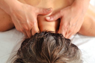 Yakın plan kadın terapist masaj masasında yatan bir hastaya profesyonel bir bacak masajı yapıyor. Spa ortamında dolaşım gelişimi ve tedavi amaçlı kas gerilimi tedavisi. 