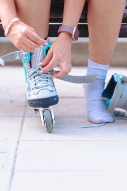 Kentteki bankta paten bağlayan, paten kayan, dışarıdaki yaşam tarzı, spor, fitness aktivitesi, dinlenme, sağlıklı eğlence, hobi.