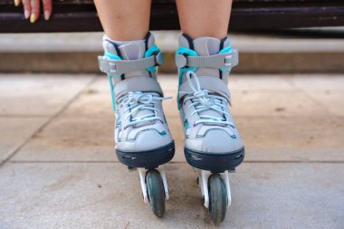 Bankta oturan bir kadının giydiği patenlerin yakın görüntüsü, açık hava yaşam tarzı, tekerleklerin ve ayakkabıların ayrıntıları, spor, spor, spor, spor, spor, spor, eğlence, yaz tatili etkinliği, modern hobi, sağlıklı yaşam tarzı.
