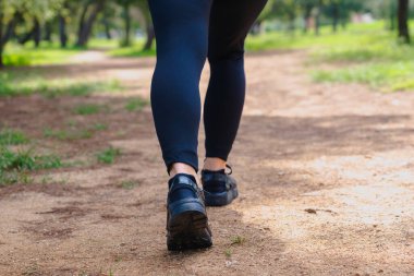 Spor kıyafetleri ve kulaklıklar takan, spor kıyafetleri ve kulaklıkla parkta koşan bir kadının tanınmaz hale gelen arka görüntüsü, spor anlayışı, sağlıklı yaşam tarzı, özgürlük, enerji, motivasyon, eğitim ve aktivite..