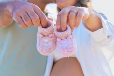 Tanımlanamayan bir çift küçük pembe bebek ayakkabılarını bir arada tutarak aşkı, umudu ve yeni başlangıçları sembolize ediyor. Yumuşak ışıkla ellerini kapat, şefkat ve mutluluk göster..