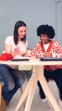 İki çok ırklı kız öğrenci masada birlikte okuyorlar kitaplar ve defterler, eğitim konsepti, takım çalışması, öğrenme, çeşitlilik, arkadaşlık, odak, işbirliği, bilgi ve akademik 