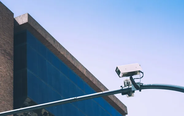 Cámara de seguridad sobre fondo de cielo azul y edificio de vidrio — Foto de Stock