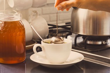 Kız çay mutfak masasının üzerinde yapar.