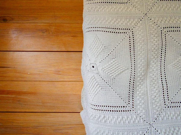 Handwoven white blanket over wooden floor — Stock Photo, Image