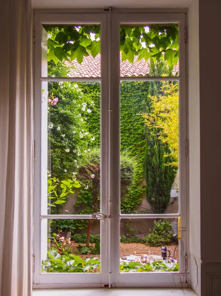 Hermosa ventana antigua hacia el patio con flores — Foto de Stock