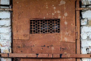 Kafes pencereli paslı metal bir kapının parçası.