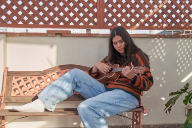 Ukulele çalan genç bir kadın, Hawaii kökenli küçük, dört telli bir müzik aleti.