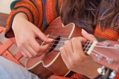 Ukulele çalan genç bir kadın, Hawaii kökenli küçük, dört telli bir müzik aleti.