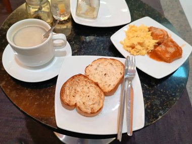Kahvaltı yuvarlak granit bir masada servis edilir; yakın çekim yukarıdan, ön planda kimse yok.
