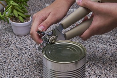 Konserve açacağının yanına konserve konservesi konservesi konservesi konservesi konserve kutusunu açmak üzere olan birinin yakın plan fotoğrafı..