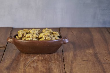 Nuts in a ceramic container on a wooden table with copy space
