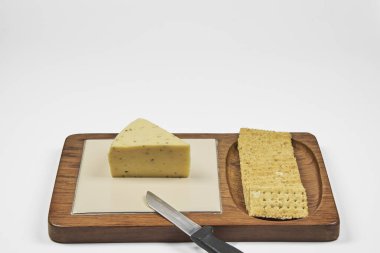 Önplanda peynir ve kraker olan tahta beyaz arkaplanda kopyalama alanı