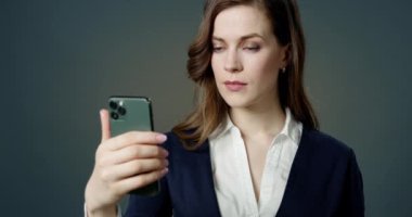 Soyut Modern Ofiste Akıllı Telefon Kullanan Güzel Genç Kadın. Yakın plan Güzel Yüzlü Beyaz İş Kadını Çevrimiçi Video İçeriği İzlerken Cep Telefonu Okuma, Bloglar, İş Bilgileri