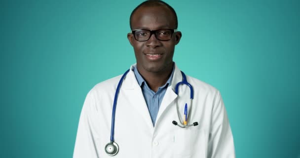 Bonito afro-americano trabalhador médico em branco casaco de laboratório sorrindo para câmera posando lento movimento. Médico do Hospital a olhar com emoções positivas. Profissional de Closeup Face no Conceito de Clínica de Saúde — Vídeo de Stock