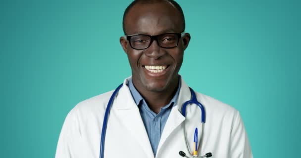 Joyeux beau docteur afro-américain riant à la caméra posant au ralenti. Professionnel médical à la clinique abstraite Regardant avec émotion positive Gros plan Visage confiant Médecin Travailleur Santé Concept — Video