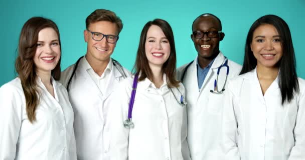 Piękny zespół młodych szczęśliwych lekarzy uśmiechających się do kamery. Międzynarodowa Grupa Medyków Udanych Zawodowo Pozowanie w Powolnym Ruchu. czarny biały mężczyźni kobiety medyczne płaszcze medycyna pracownicy szacunek. — Wideo stockowe