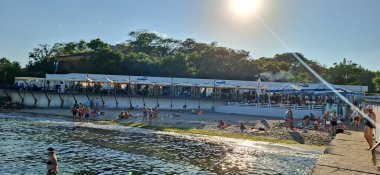 Sahil kenarında güneşli bir sahil günü ve deniz kenarında güneşli bir günün tadını çıkaran insanlarla dolu bir kumsal..