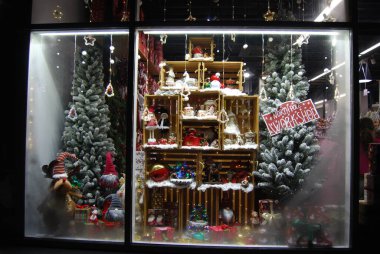Cüceler ve ağaçlarla süslü Noel vitrinleri. Cüceler, kar ve tatil süsleriyle süslenmiş rafların yer aldığı Noel mağazası vitrinleri..
