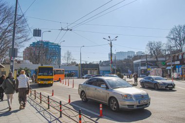 Arabaları, otobüsleri ve yayaları olan gündüz vakti şehir caddesi.