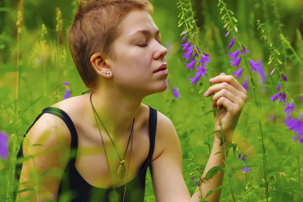 La chica en el jardín oliendo una flor — Foto de Stock