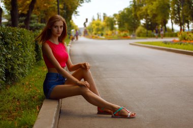 Parkta kaldırım kenarında oturan kız