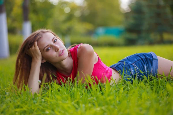 Fille couchée dans l'herbe épaisse, soutenant la tête avec la main — Photo