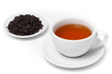 Beyaz fincan taze demlenmiş Seylan Kandy Orange Pekoe çayı tabağında kurumuş siyah çay yaprakları, beyaz arka planda izole..