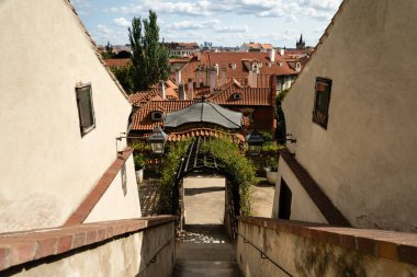 Çek Cumhuriyeti 'nin orta Prag kentinde yaz güneşinde yakalanan tarihi basamaklar ve şehir çatıları manzaralı kemer yolu