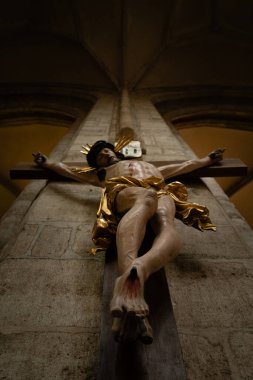 Aziz Barbara Katedrali 'nin içindeki Gotik bir sütunun yaldızlı detaylarıyla süslü, barok bir haçın dramatik alçak açılı görüntüsü, Kutna Hora