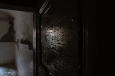 Terk edilmiş bir evin içindeki eski bir ahşap kapıya koyu kahverengi boya yakın plan.